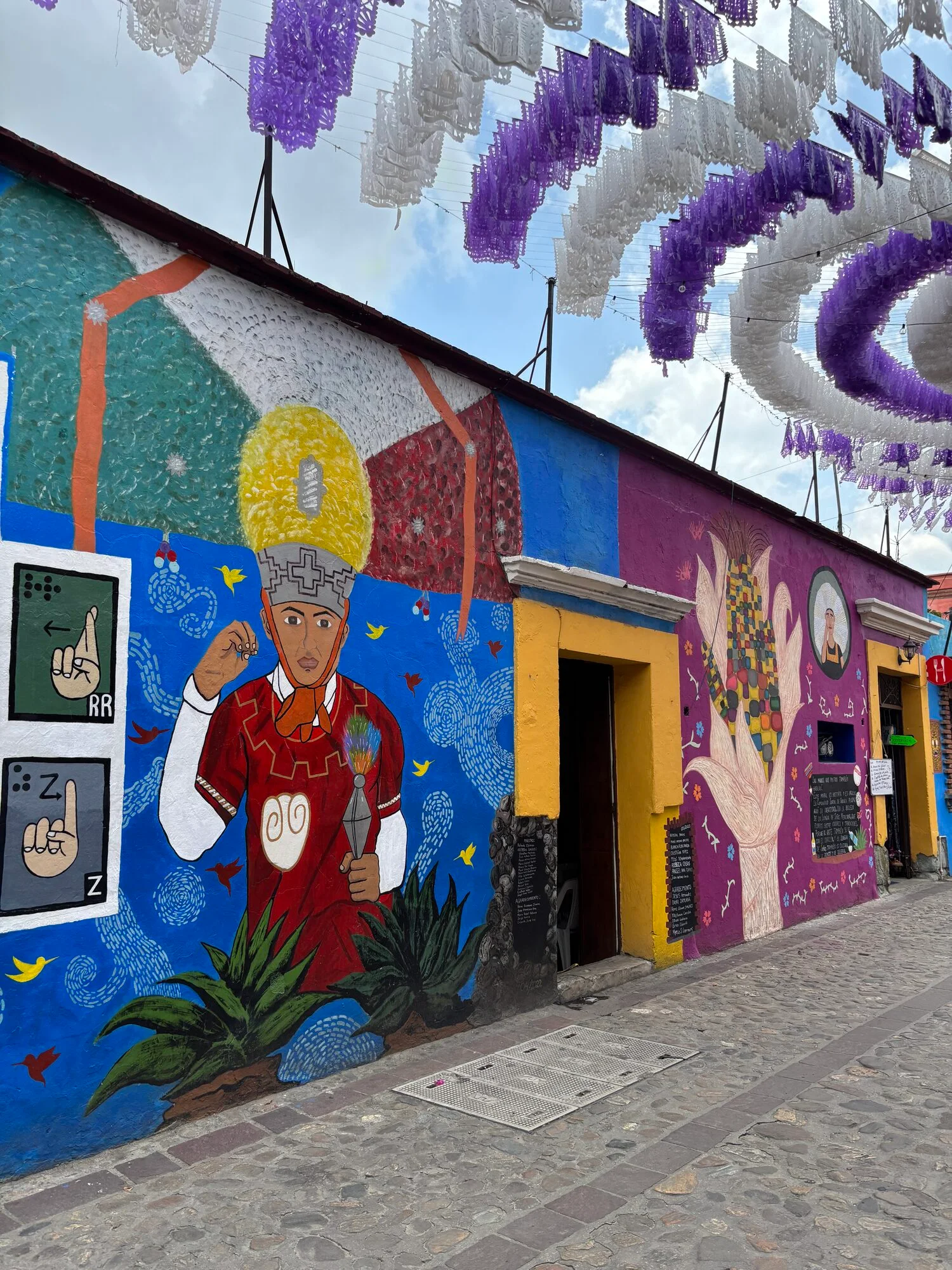 Murales coloridos y papel picado en una calle de Jalatlaco, Oaxaca